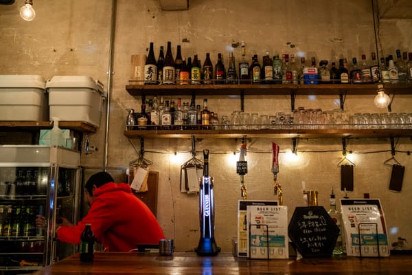 The owner Tasuku-san behind the bar of Penguin Parade getting ready some beers from the fridge.